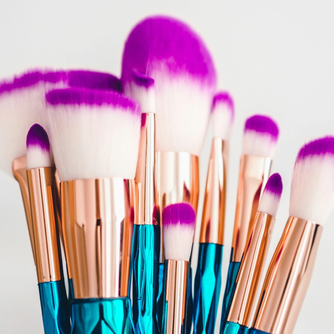 Blue, gold, and purple makeup brushes, like those that must be cleaned routinely to prevent eye and skin infections from makeup and applicators.