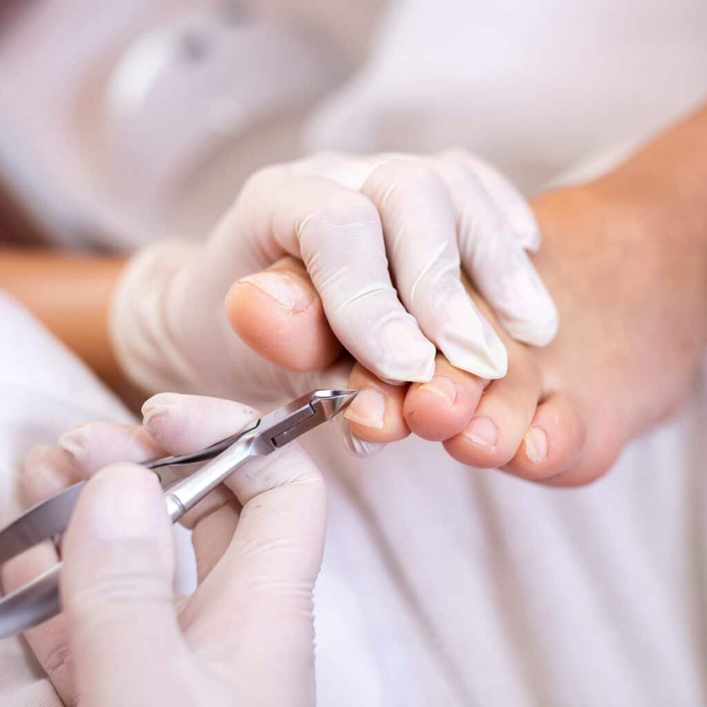 Picture of a nail technician doing a cut during a pedicure.