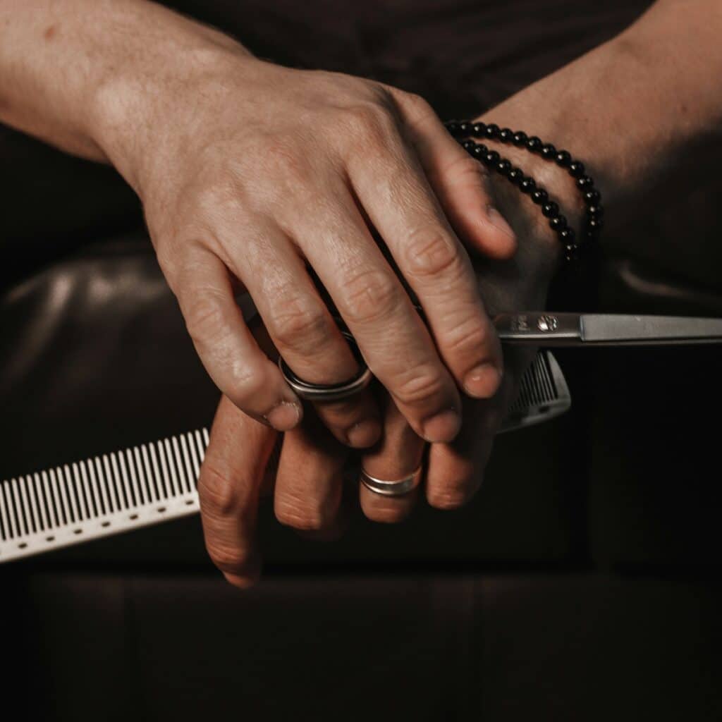 A hair stylist holding scissors with a repetitive strain injury from hairdressing