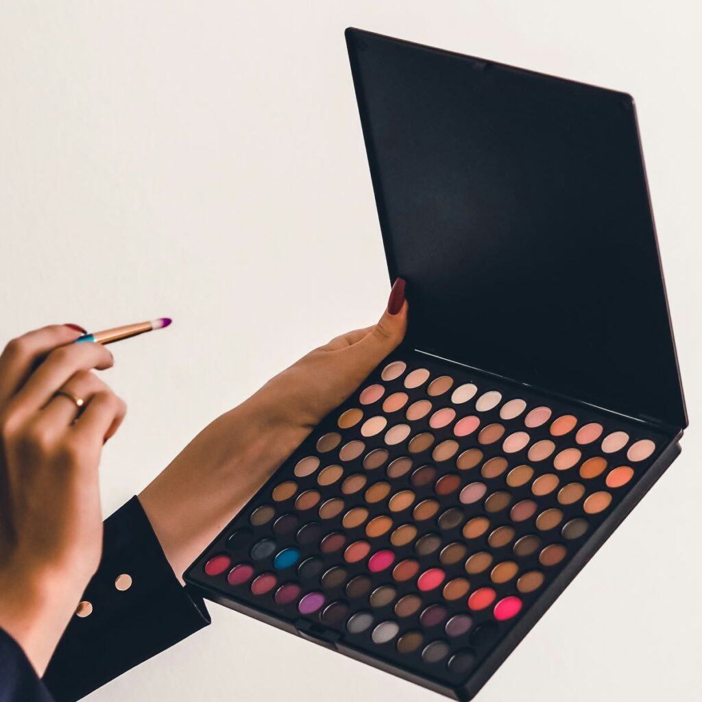 Women holding brush and colored eyeshadow palette that could carry toxins in makeup like carcinogenic makeup