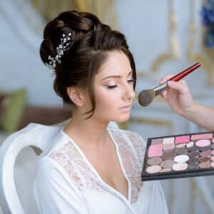 Bride getting makeup done by a makeup artist who is considering makeup artist policies like refunds and cancellation