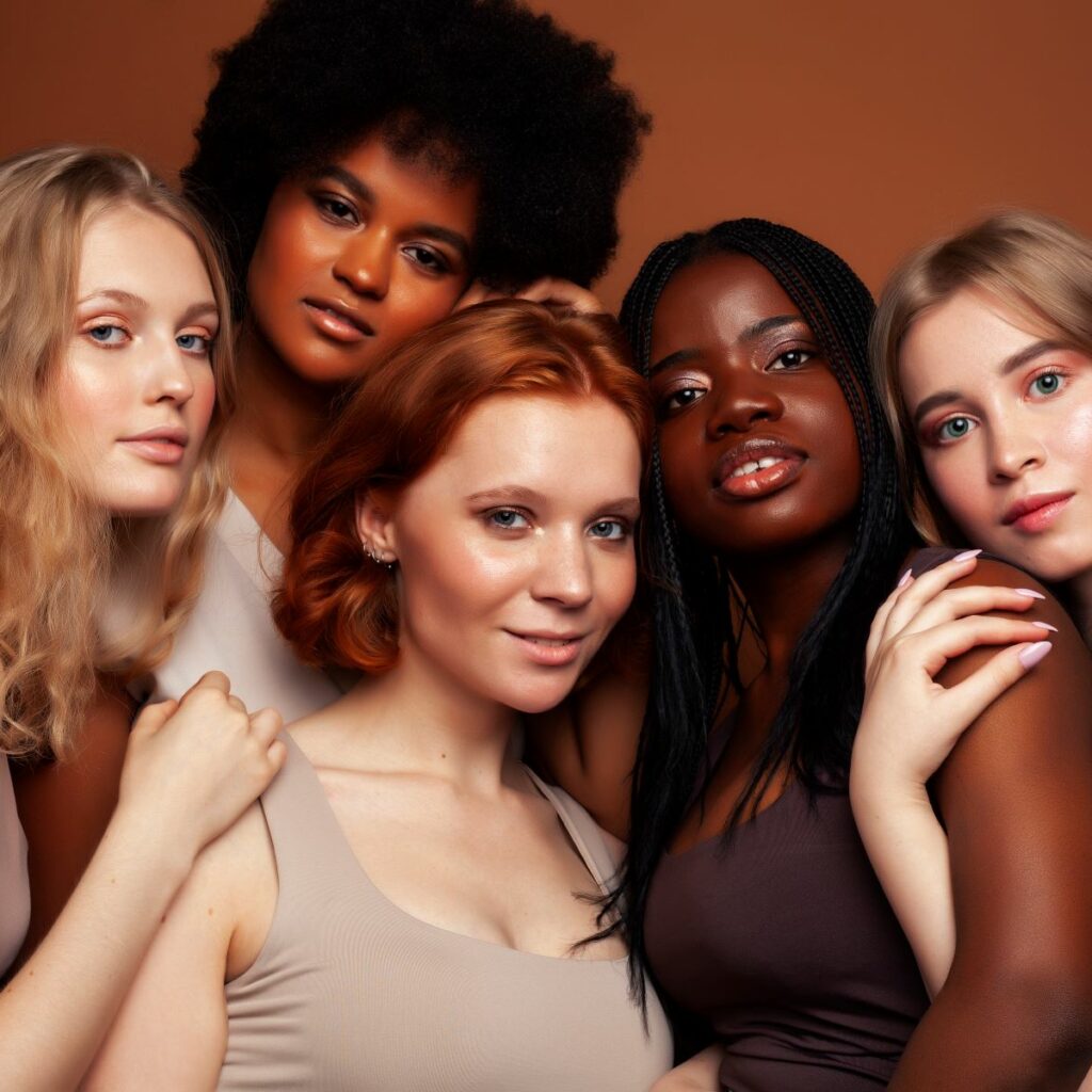 Five women pose together in one photo, representing different types of hair and ethnicity. Learning how to style different hair types is crucial for inclusion and serving happy clients.