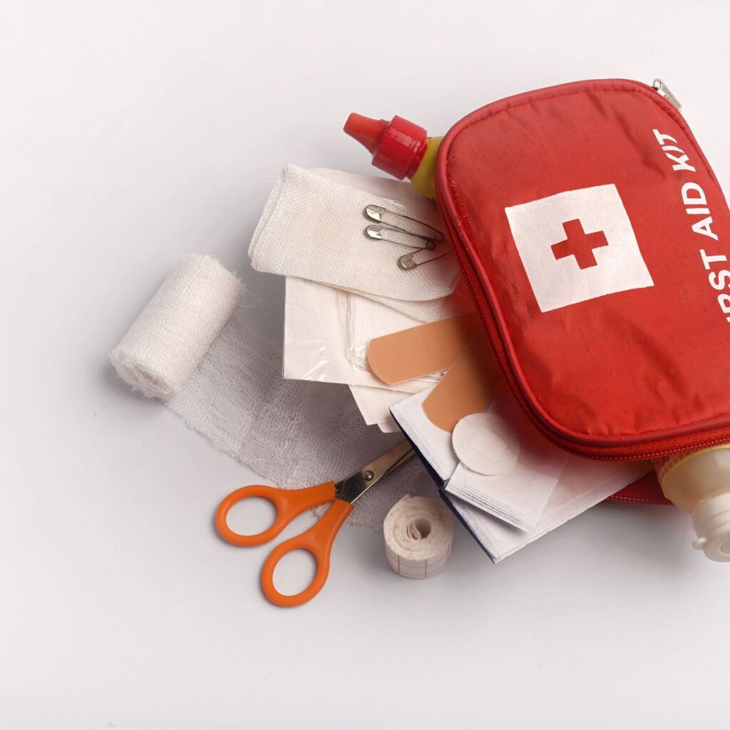 A hair salon first aid kit displayed with gauze, scissors, band-aids, and other first aid safety supplies a hair salon might need.