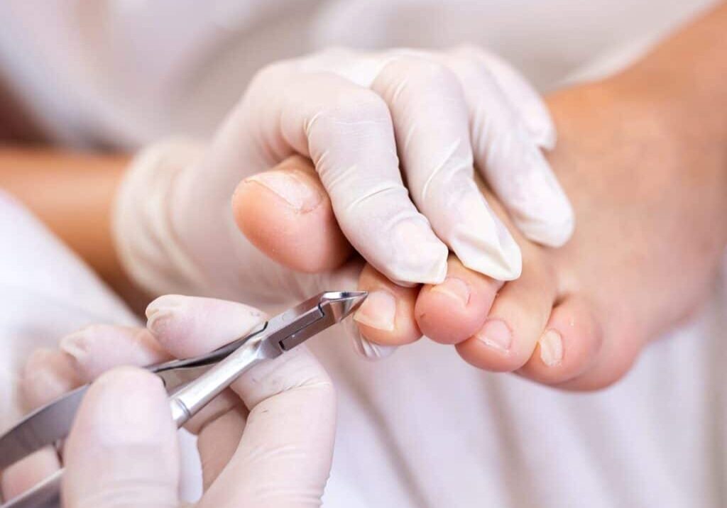 Picture of a nail technician doing a cut during a pedicure.