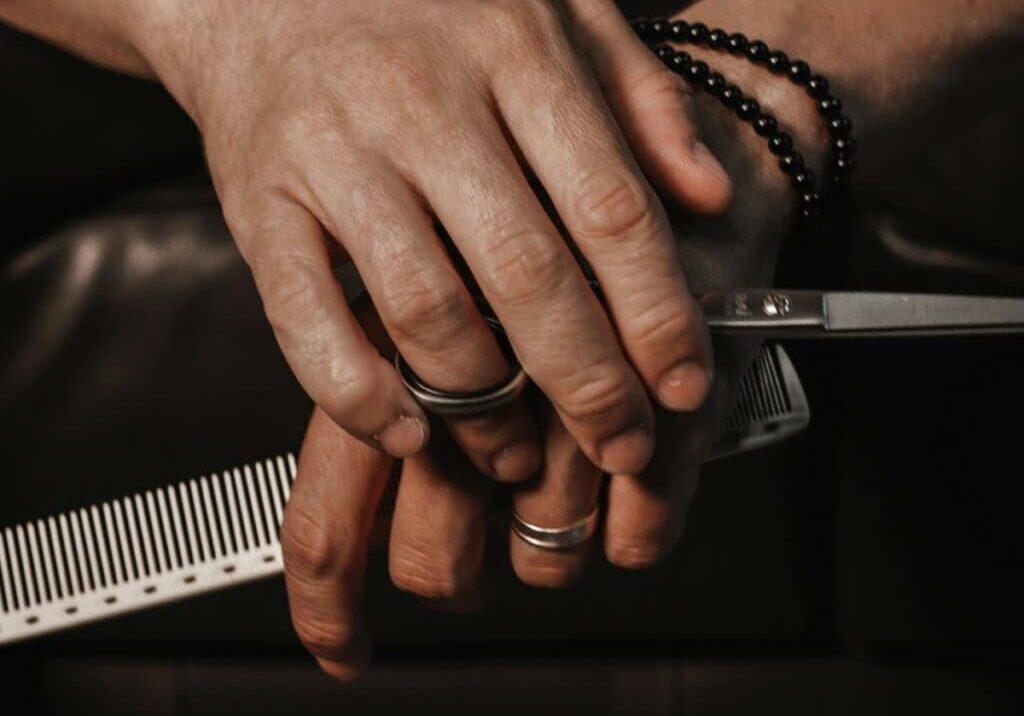 A hair stylist holding scissors with a repetitive strain injury from hairdressing