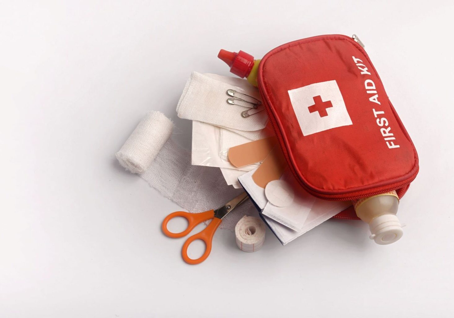 A hair salon first aid kit displayed with gauze, scissors, band-aids, and other first aid safety supplies a hair salon might need.