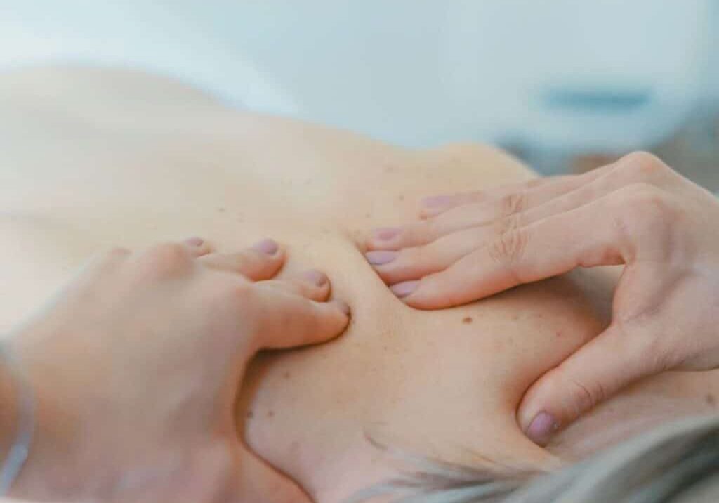 Massage therapist massaging older woman’s back representing dealing with difficult customers and massage therapy complaints