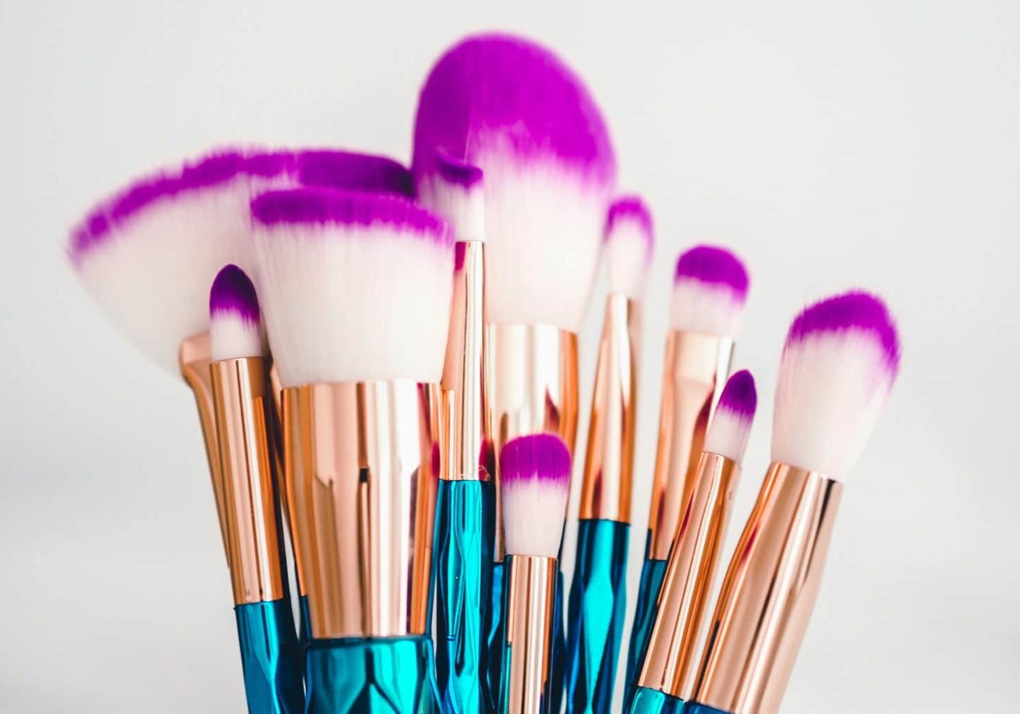 Blue, gold, and purple makeup brushes, like those that must be cleaned routinely to prevent eye and skin infections from makeup and applicators.