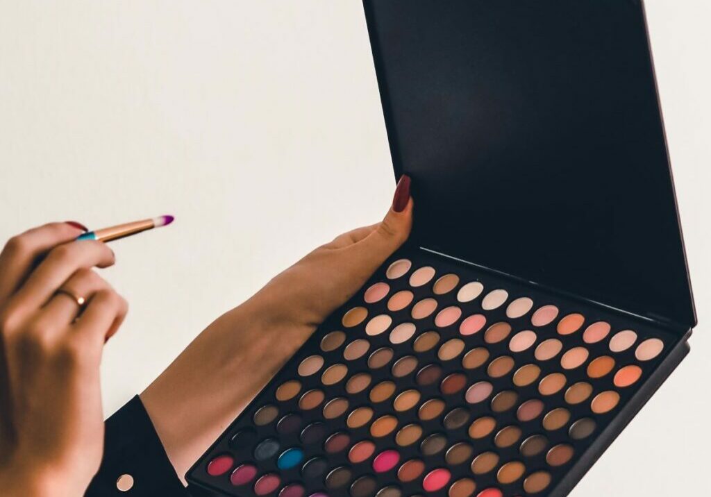 Women holding brush and colored eyeshadow palette that could carry toxins in makeup like carcinogenic makeup