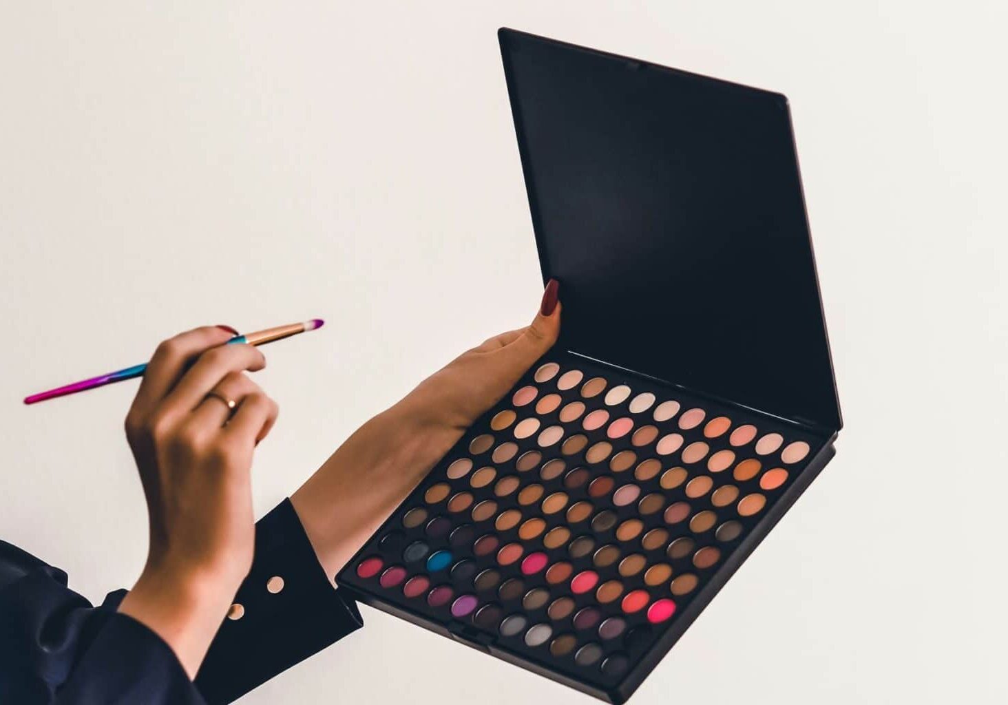 Women holding brush and colored eyeshadow palette that could carry toxins in makeup like carcinogenic makeup